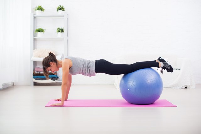 Woman doing push-ups on the floor with fit ball