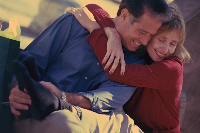 Woman sitting and hugging man, man rubbing her feet