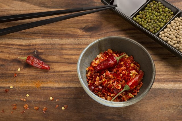 Cayenne pepper, soy sauce and chopsticks on the wooden table.