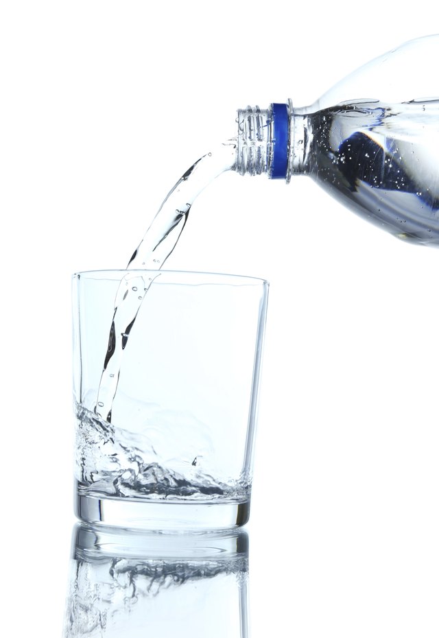 Pour water from bottle into glass, on light blue background