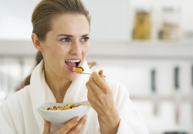 Young housewife having healthy breakfast in kitchen