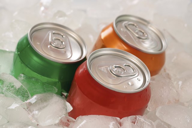Cold cola and lemonade in cans on ice cubes