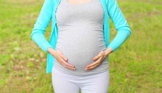 Pregnant young woman outdoors in summer day closeup