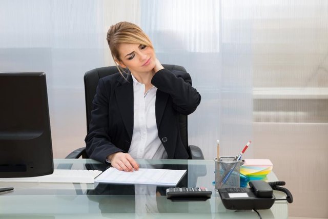 Portrait Of Young Businesswoman Suffering From Neckache In Office