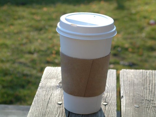 A lone coffee cup on a picnic table.