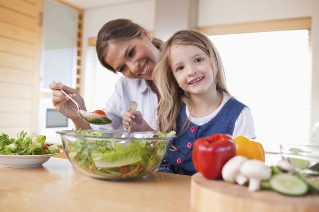 Happy mother and her daughter preparing a salad