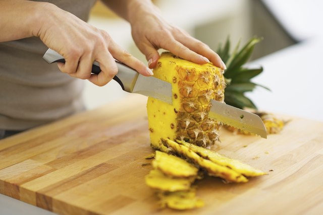 closeup on woman cutting pineapple