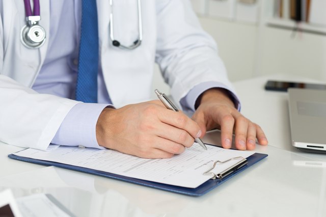 Close up of doctor's hands writing prescription