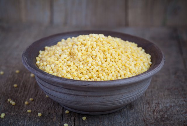 Dry Israeli couscous ptitim in clay bowl on wooden table