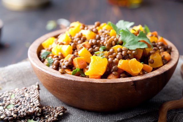 Lentil with carrot and pumpkin ragout in a wooden bowl.