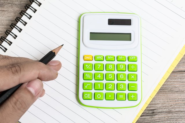 Hand Hold Pencil with Calculator Placed on Notebook