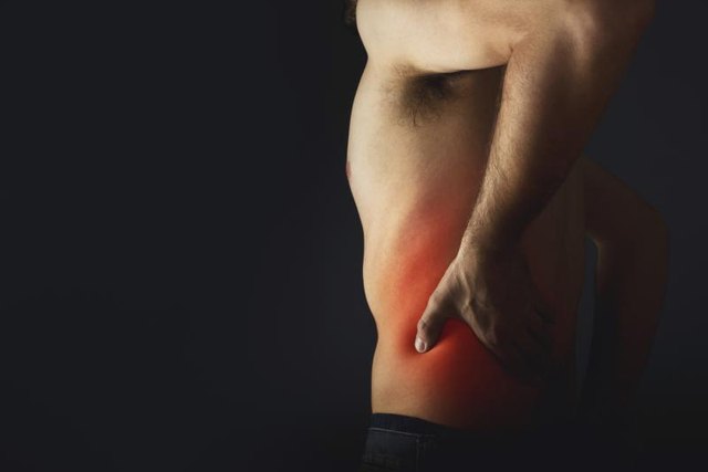 Backache. Pain in the lower back. Shirless man touching his back for the pain.