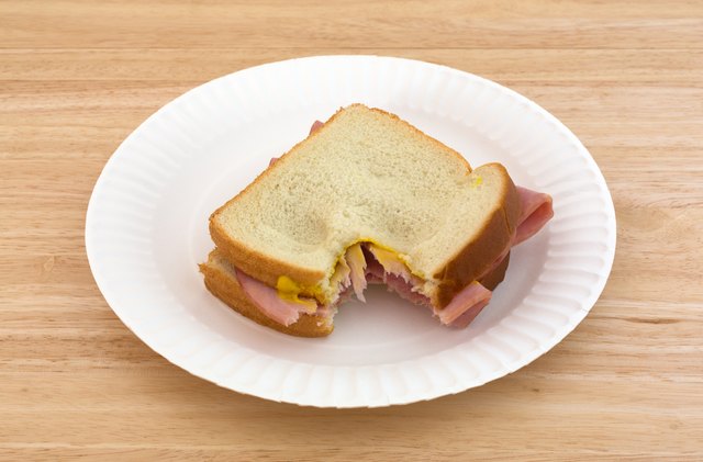 Honey ham sandwich on a paper plate bitten