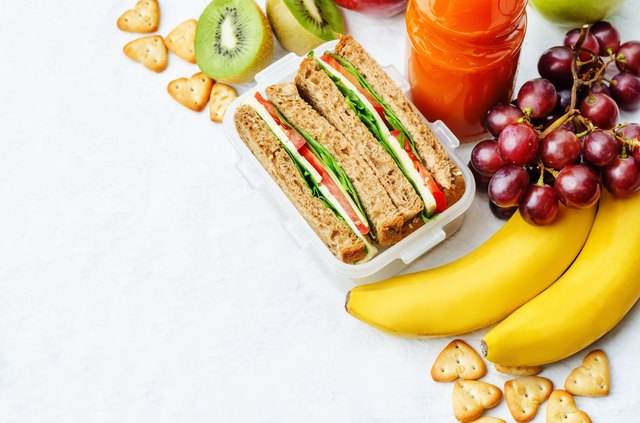 school lunch with a sandwich, fresh fruits, crackers and juice