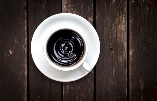 Closeup of black coffee from top view on vintage wood background.