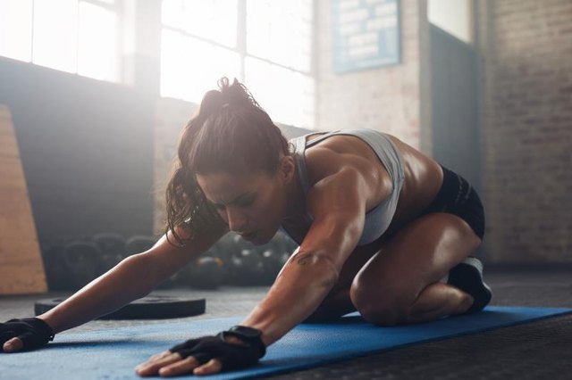 Shot of a young woman doing yoga on the gym floor. Muscular female doing stretching workout at health club.