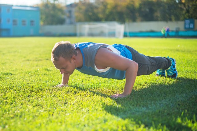 sport man stretching at the park, ddoing push-ups on grass