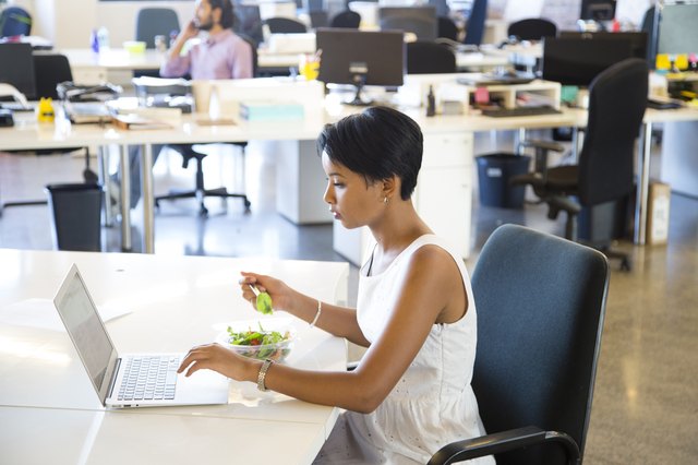 Businesswoman eating lunch in an open plan office