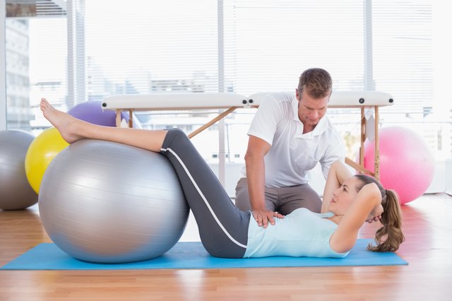 Trainer working with woman on exercise mat