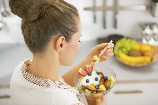 young housewife eating fresh fruit salad. rear view