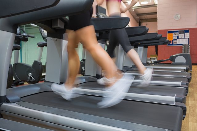 Two people running on treadmills in the gym