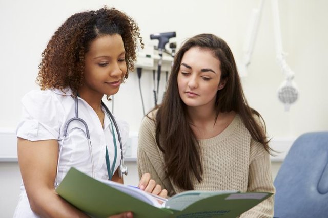 Nurse Showing Patient Test Results Holding Folder Whilst Sitting Down