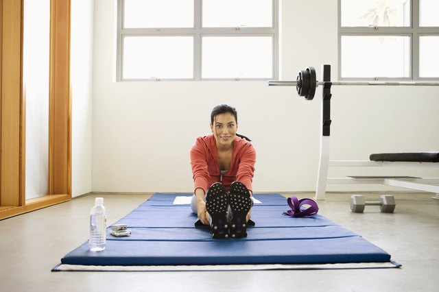 Woman doing stretching exercises on mat in gym