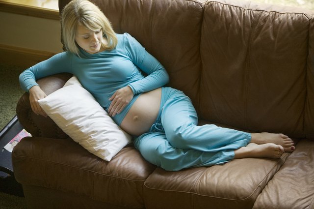 Pregnant woman lying on sofa in sitting room