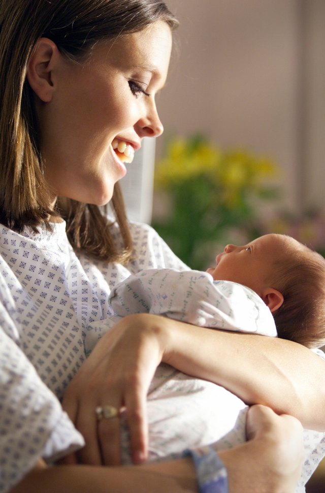 a young caucasian mother holds and admires her new baby girl