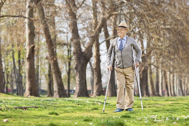 Senior gentleman walking with crutches outdoors
