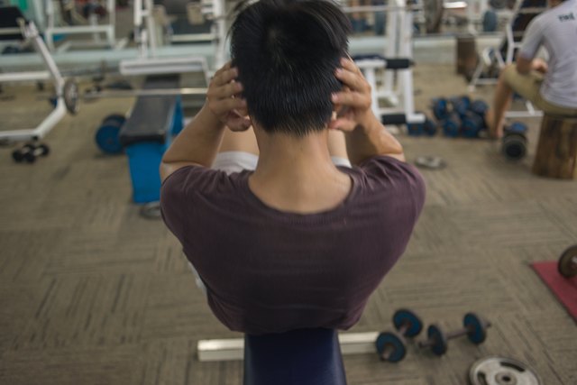 Young man exercising doing sit-ups indoors for diet