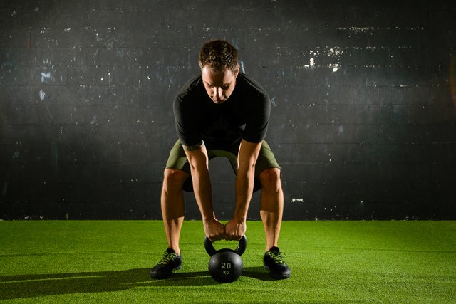 Athlete lifting heavy weight with Kettle-bell