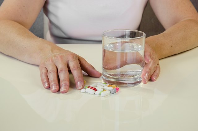 hand with pill and glass of water