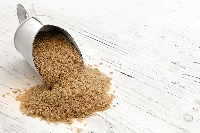 Scoop of Brown Rice on Rustic White Timber