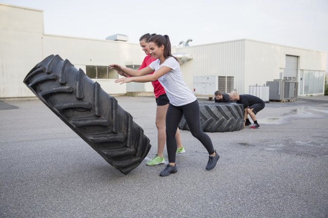 Group of people flipping heavy tires as workout