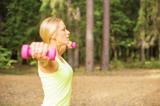 Active woman working out outdoors with dumbbells