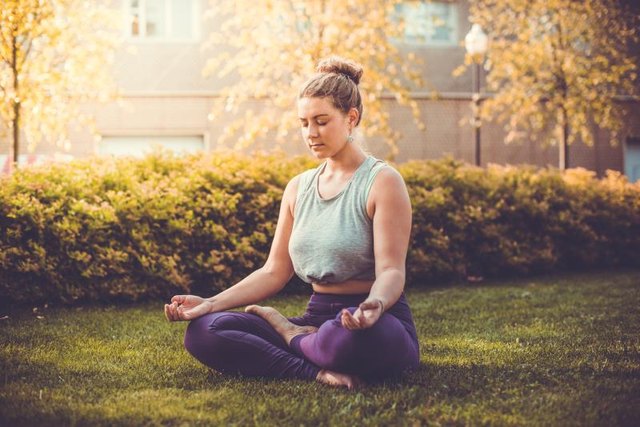 Yoga meditation in lotus pose in park. Young woman in peace, soul and mind zen balance concept. Toned picture
