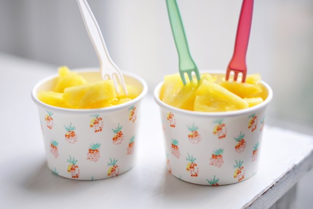 Two paper cups filled with pineapple chunks