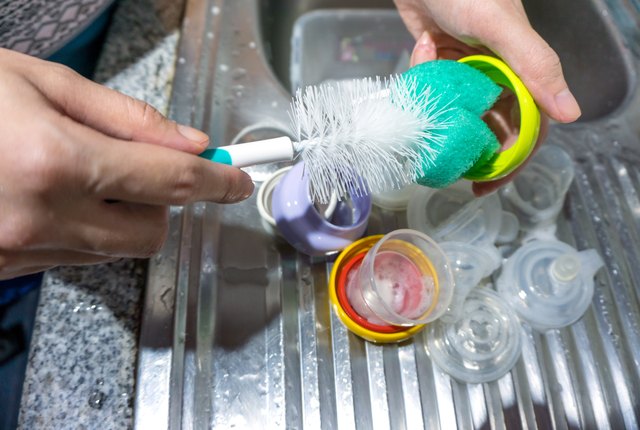 Mother washing baby milk bottle