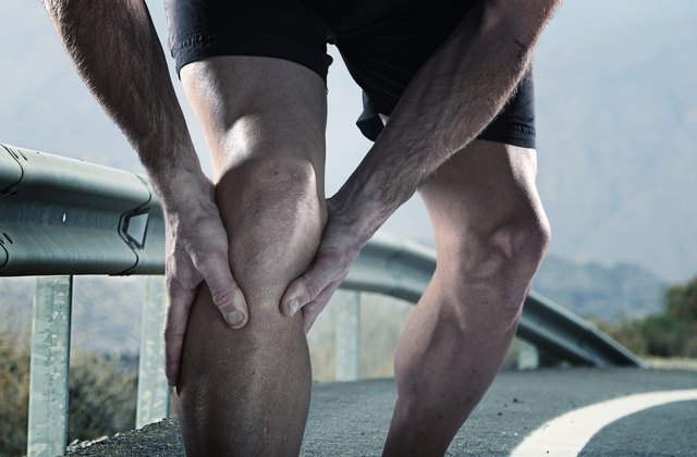 runner with athletic legs holding knee suffering muscle pain