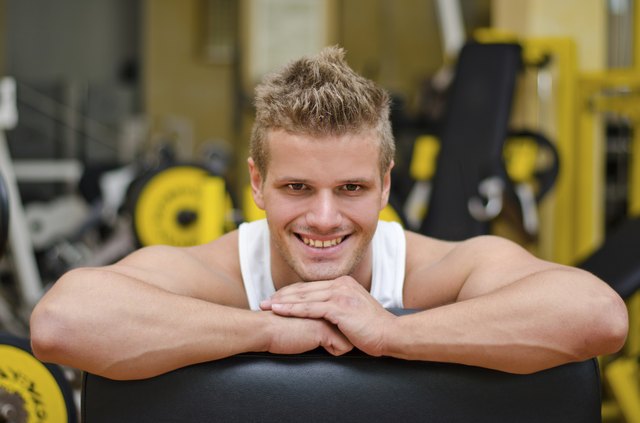 Attractive young man in gym resting on equipment