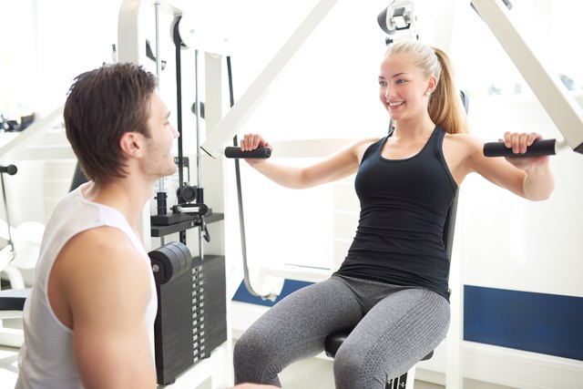 Trainer Assisting Woman on Chest Press Machine