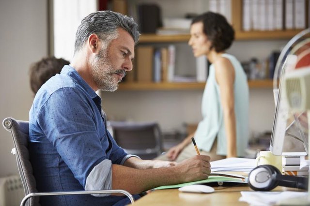 Side view of businessman writing at desk in office