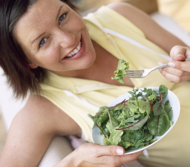Healthy eating. Woman eating salad leaves. Fruit and vegetables are rich in minerals and vitamins, as well as being low in fat. Green vegetables are particularly rich in iron, an essential mineral in the body.