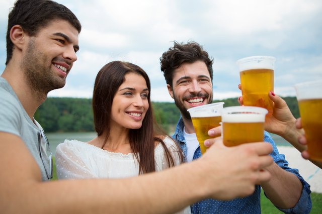 Group of friends toasting with beer in plastic glasses