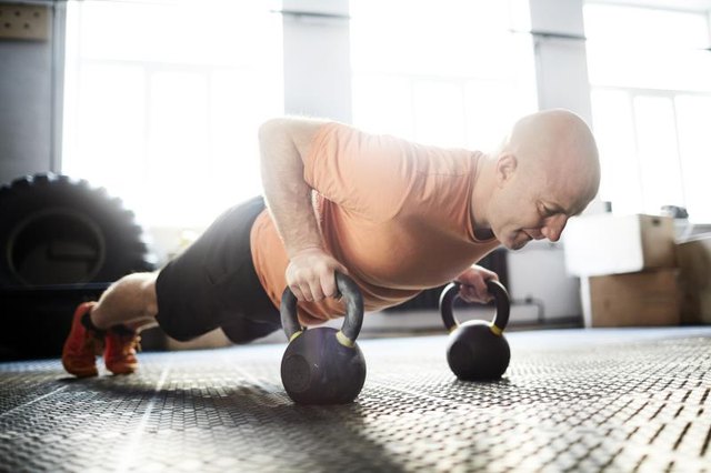 Active young man doing push-ups with kettlebells