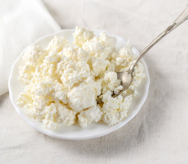 Plate of homemade cottage cheese on white tablecloth.