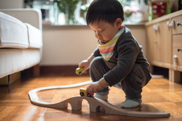 Crouching toddler boy playing toy train