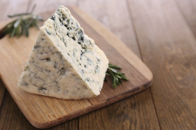Tasty blue cheese with rosemary, on wooden table