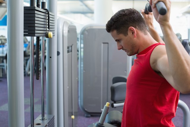 Strong bodybuilder using weight machine for arms
